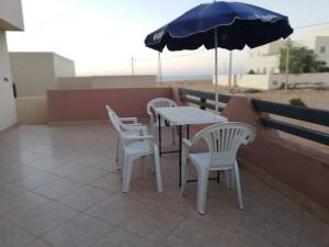 Duas cadeiras e uma mesa com um guarda-sol na varanda em La Perle de L'ocean N03 RDC em Akhfennirr