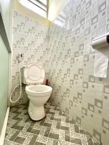 a bathroom with a toilet with gray tiles at Unique apartment 2 in Mombasa