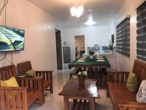 a living room with tables and chairs and a television at Taylors Country Home/Travellers Inn- The Bungalow in Catarman