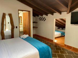 a bedroom with two beds and a flat screen tv at HOTEL ENCANTO COLONIAL in Villa de Leyva