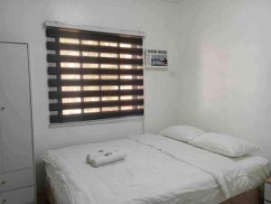 a white bedroom with a bed and a window at Taylors Country Home/Travellers Inn- The Bungalow in Catarman