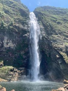 a waterfall on a mountain with a body of water at Pousada Filhos da Canastra in Vargem Bonita