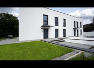 un edificio blanco con un patio de césped delante de él en Blauer Stein Apartments Doppelzimmer 1, en Pulheim