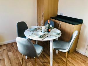 una mesa blanca con sillas y platos y una botella de vino en Lavender Cottage en Thirsk