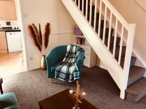a living room with a green chair and stairs at Lavender Cottage in Thirsk