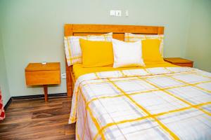 um quarto com uma cama grande e almofadas amarelas em EIREANN HOUSE Yassa em Douala