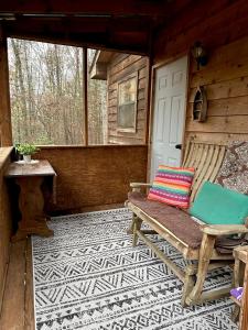 un porche de una cabaña con banco y puerta en Private cozy cabin in the woods with great view, en Murphy
