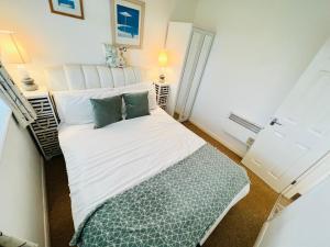 um pequeno quarto com uma cama branca e almofadas verdes em 2 Bedroom Chalet SB109, Sandown Bay, Isle of Wight em Brading