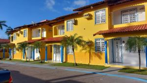 a yellow building with palm trees in front of it at Salinopolis- casa com piscina in Salinópolis