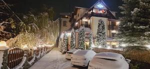 una casa cubierta de nieve por la noche con luces en Hotel Bran Stoker, en Bran