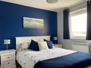 1 dormitorio con paredes azules y 1 cama con almohadas en Menai View, an apartment with amazing sea views, en Y Felinheli