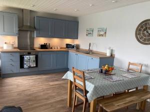una cocina con armarios azules y una mesa con sillas en Menai View, an apartment with amazing sea views, en Y Felinheli
