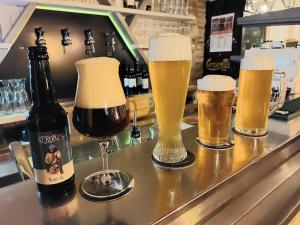 three glasses of beer sitting on a bar at Affittacamere Al Canyon PUB BIRRERIA in Fondo