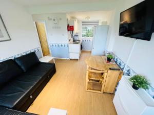 uma sala de estar com um sofá preto e uma mesa em 2 Bedroom Chalet SB57, Sandown, Isle of Wight em Brading