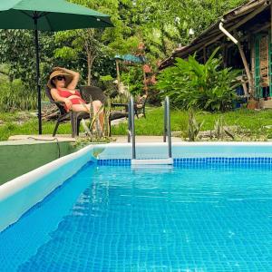 a woman sitting in a chair next to a swimming pool at El Cielo Biohospedaje in Tena