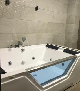 a white bath tub with a glass window in a bathroom at Stelar Hostal in Cuenca