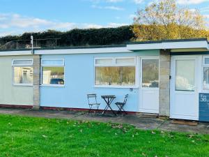 a house with two chairs and a table in front of it at 2 Bedroom Chalet SB57, Sandown, Isle of Wight in Brading