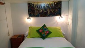 a bed with two green pillows and a painting on the wall at Cusco Plaza de Armas in Cusco