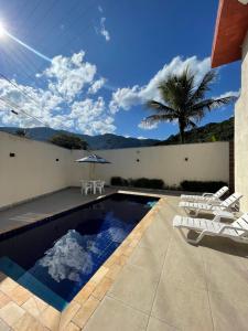 a swimming pool with chairs and a palm tree at Residencial 220 Maresias in Maresias