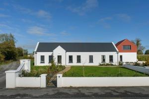 ein weißes Haus mit einem Zaun davor in der Unterkunft Red Sheds Villa Portarlington 