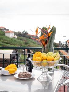 un bol de fruta en una mesa con una botella de vino en The House of Passos, en Ponta do Sol