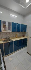 eine Küche mit blauen Schränken, einer Spüle und einem Kühlschrank in der Unterkunft استراحة الأولين in Dschidda