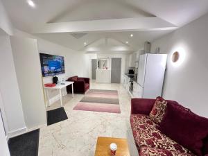 een woonkamer met een bank en een koelkast bij Cozy Luxury Private Cottage in Greenford