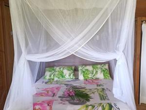 a bed with a canopy with pink and green pillows at Ma cabane in Deshaies