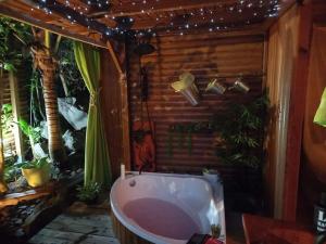 - une salle de bains avec baignoire dans une chambre ornée de plantes dans l'établissement Ma cabane, à Deshaies