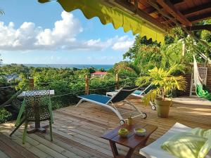 une terrasse avec des chaises et une table et une vue sur l'océan dans l'établissement Ma cabane, à Deshaies