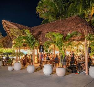 a group of people sitting in a restaurant with palm trees at Villa Familiar con Alberca Privada en Tulum Country Club Riviera Maya in Akumal
