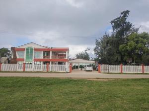 a house with a white fence in front of a street at LATA HOTEL in Hofoa
