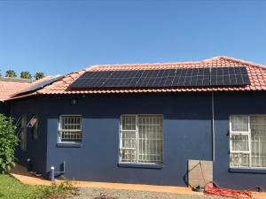 una casa azul con paneles solares en el techo en The Plum, en Louis Trichardt