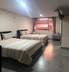 a hotel room with two beds and a window at Stelar Hostal in Cuenca