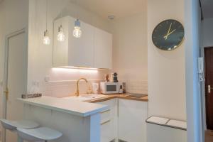 ランスにあるLa verrière Rémoiseのシンクと壁に時計が付いたキッチン