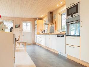 a kitchen with white cabinets and a tv on the wall at 5 person holiday home in Dannemare-By Traum in Dannemare +42 photos