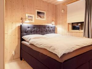 een groot bed in een kamer met houten wanden bij Holiday home Dannemare XLIII in Dannemare