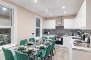 a kitchen with a table and green chairs in a kitchen at Convenient spacious house next Seven sisters station London in London