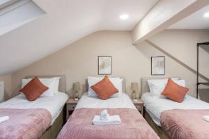 een zolderkamer met 2 bedden en oranje kussens bij Convenient spacious house next Seven sisters station London in Londen