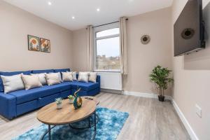 a living room with a blue couch and a table at Convenient spacious house next Seven sisters station London in London