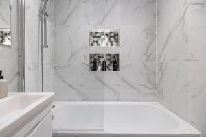 baño blanco con ducha y lavamanos en Convenient spacious house next Seven sisters station London en Londres