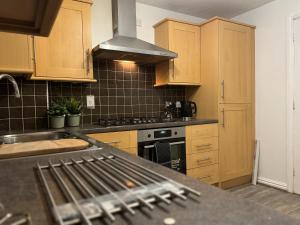 a kitchen with wooden cabinets and a stove top oven at Rooms Near Me - Central Birmingham Free Parking in Birmingham