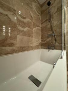 a bathroom with a bath tub with a shower at Rooms Near Me - Central Birmingham Free Parking in Birmingham