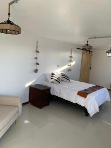 een witte slaapkamer met een bed en een bank bij Loft la herradura in Coquimbo