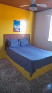 a bedroom with a blue bed with a yellow wall at Aluga-se apartamento em Ponta de Areia in Itaparica