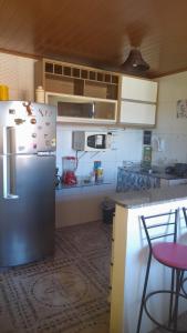a kitchen with a refrigerator and a counter with chairs at Aluga-se apartamento em Ponta de Areia in Itaparica Town