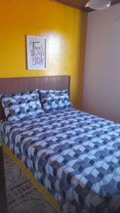 a bed with a blue and white comforter in a room at Aluga-se apartamento em Ponta de Areia in Itaparica Town