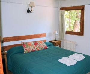 a bedroom with a green bed with towels on it at Cabañas Rucaleufu in San Martín de los Andes