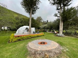 a tent in a park with a fire pit in the grass at Hosteria Totoral in Ibarra
