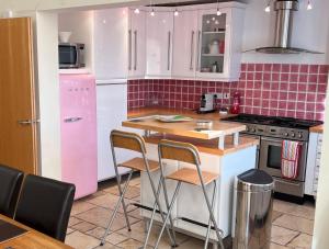 uma cozinha com electrodomésticos cor-de-rosa e um balcão com bancos em East Belfast Townhouse em Belfast